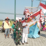 Kades Sembunganyar, Kc. Dukun, Abdul Khobir dengan mengenakan kostum tentara dengan latarbelakang kreasi perahu saat ikuti karnaval. FOTO: SYUHUD/BANGSAONLINE.