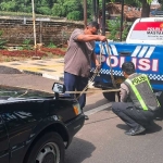 Petugas dari Satantas Polres Tuban saat membantu pengendara mobil yang mogok.