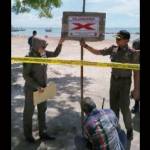 Kasi Ops Satpol PP, Agung Endro ketika memasang papan penutupan lahan reklamasi pantai Delegan. foto: syuhud/ BANGSAONLINE