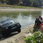 RAMAI-RAMAI. Warga saat membantu mengevakuasi mobil yang tercebur di sungai. (foto: dendi martoni/BANGSAONLINE)