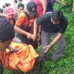 Petugas dibantu warga saat mengevakuasi jasad korban dari Sungai Bengawan Solo.