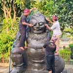 Idris, Juru Pelihara Arca Totok Kerot (kiri) dibantu dua rekannya saat membersihkan arca Totok Kerot. Foto: MUJI HARJITA/ BANGSAONLINE