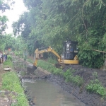 Petugas sedang mengeruk saluran air.