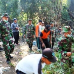 Para anggota Kodim Madiun berbaur dengan warga bersihkan lingkungan bekas banjir.