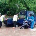 Petugas Kepolisian membantu mendorong mobil yang mogok akibat banjir.