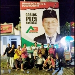 Para milenial pendukung Cakades Abdul Khamid foto bersama dengan latar belakang poster cakades tersebut. foto: SYUHUD/BANGSAONLINE