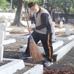 Kapolres Gresik AKBP Arief Fitrianto saat membersihkan Taman Makam Pahlawan. (foto: SYUHUD/BANGSAONLINE)