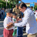 Wakil Ketua DPRD Kota Kediri, Katino, saat membagikan susu dan roti gratis kepada para pelajar. Foto: Ist