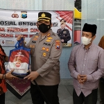 Ketua MPC PP Kota Kediri Danan Prabandaru saat menerima bantuan paket sembako secara simbolis dari Kapolres Kediri Kota AKBP Wahyudi disaksikan oleh Ketua PCNU Kota Kediri K.H. Abu Bakar Abdul Jalil dan Duta Prokes serta Duta Vaksin. (foto: MUJI HARJITA/ BANGSAONLINE)