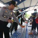 Petugas gabungan saat menyemprotkan cairan disinfektan ke bangku di ruang tunggu terminal Kota Sampang.