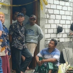 Mahfud (45), suami korban, terduduk di depan pintu belakang rumah disaksikan polisi saat olah TKP. Foto: Ist.