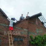 Sejumlah warga bergotong-royong memperbaiki genting rumah yang rusak akibat terjangan angin kencang. foto: RONY S/ BANGSAONLINE