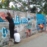 Warga bersama-sama menggambar tembok Sungai Grindulu sebagai wahana edukasi akan pentingnya kelestarian lingkungan sungai.