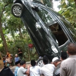 Warga memadati lokasi kejadian saat mobil ditarik menggunakan alat berat.