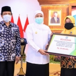 Gubernur Jatim Khofifah Indar Parawansa didampingi Kepala Biro Kesejahteraan Rakyat Pemprov Jatim Gatot Subroto saat menyerahkan beasiswa untuk guru madin secara simbolis.