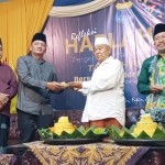 Kiai Asep memberikan potongan gunungan tumpeng kepada pengurus senior PMII Mojokerto.