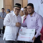Direktur SDM dan Hukum Semen Indonesia Agung Yunanto (kiri) secara simbolis menyerahkan beasiswa kepada perwakilan siswa.