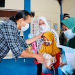 Dr Meithiana Indrasari, S.T., M.M. dan M Zurqoni menyerahkan sandal kepada para anak yatim dan dhuafa di Pendopo Stikosa-AWS Surabaya, Jumat (15/10/2021). foto: ist
