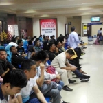 Pengurus paspor tertib mengantre dengan duduk. 