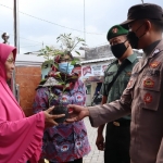 Bhabinkamtibmas Polsek Manyar dan Koramil Manyar saat memberikan bantuan pohon cabai. foto: SYUHUD/BANGSAONLINE.com
