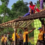 Petugas dibantu warga saat sedang memperbaiki rumah yang terkena longsor. (Ist).