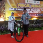 Kepala Dinsos P3A Kota Mojokerto saat menyerahkan hadiah kepada salah satu lansia.