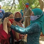Zainab Zuraidah saat memasangkan masker kepada salah seorang pengunjung Taman Paseban yang tidak menggunakan masker di Taman Paseban Bangkalan, Senin (17/8). foto: AHMAD FAUZI/ BANGSAONLINE