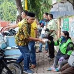 Jajaran DPD Golkar, Fraksi Golkar, dan AMPI membagikan nasi bungkus dan masker kepada para ojol. Berharap meringankan beban hidup akibat Covid 19. foto: YUDI EP/ BANGSAONLINE