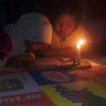 Dua bocah harus belajar menggunakan lilin karena pemadaman listrik. foto: BANGSAONLINE