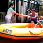 Petugas sedang memberikan nasi bungkus ke warga terdampak banjir.