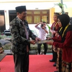 Kepala Kanwil Kemenag Jatim Drs. H. Syamsul Bahri, M.Pdi saat menyerahkan penghargaan kepada siswa/i terbaik di acara wisuda, Senin (28/05). foto: IWAN/ BANGSAONLINE