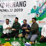 Ketua DPC PKB Gresik Moh. Qosim menyerahkan potongan tumpeng pada calon Ketua DPRD Fandi Ahmad Yani. foto: SYUHUD/ BANGSAONLINE