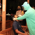 Petugas melakukan swab antigen terhadap salah satu pengunjung cafe yang melanggar jam malam.