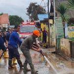 Pj Bupati Probolinggo, Ugas Irwanto, saat ikut membersihkan puing-puing sisa banjir dan lumpur yang menggenangi jalan.
