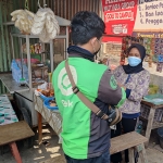 Wartik, pemilik "Warung Nasi Campur Babe" saat menyerahkan pesanan kepada driver Gojek untuk diantar kepada pelanggan.