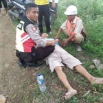 Korban luka parah akibat sepeda motornya terperosok di jalan yang berlubang. Tampak petugas sedang menolong korban.