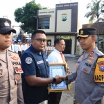 Kapolres Kediri Kota AKBP Bramastya Priaji saat menyerahkan penghargaan kepada Surya, anggota Tim Humas Polres Kediri Kota. Foto: Ist.