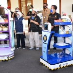 Gubernur Jawa Timur Khofifah Indar Parawansa saat menerima dua robot KECE dari Rektor Unesa, Prof. Dr. Nurhasan di halaman Gedung Negara Grahadi, dalam rilisnya kepada BANGSAONLINE.com, Senin (13/7/2020). foto: MMA/ bangsaonline.com