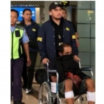 DPO Midhol duduk di kursi roda dengan kedua betis  tertembak didorong petugas di bandara dengan pengawalan ketat. FOTO: ist.