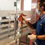 Karyawan menyemprotkan disinfektan ke pintu salah satu hotel untuk mencegah virus Corona.