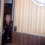 Tampak salah satu penyidik sedang mengintip di pintu masuk kantor Kejari Gresik. foto: SYUHUD/ BANGSAONLINE