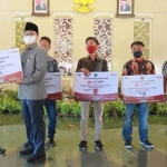 Bupati Pamekasan Baddrut Tamam saat menyerahkan bantuan CSR dari Bank Jatim di Mandhapa Agung Ronggosukowati.