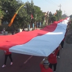 Ribuan Warga membentangkan bendera merah putih keliling kampung. foto: RONY S/ BANGSAONLINE