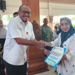 Asisten Pemerintahan dan Kesejahteraan Rakyat Sekdakot Mojokerto, Heryana Dodik Murtono, saat menyalurkan bantuan modal usaha dari DBHCHT 2025 kepada salah satu penerima.