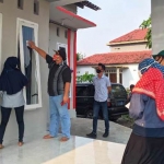 Eka Wisnu Wardana, Komisioner KPU Kabupaten Kediri Div. Perencanaan, Data, dan Informasi bersama PPDP saat menempelkan stiker di rumah warga yang sudah dicoklit. (foto: ist.)