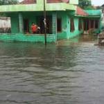 Warga sedang melihat genangan banjir di depan rumahnya. foto: rahmatullah/ BANGSAONLINE