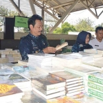 Wabup Moh. Qosim sedang membaca buku dalam pameran buku. foto: SYUHUD/ BANGSAONLINE