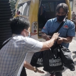 Petugas saat membagikan paket ikan kepada warga. (foto: ist)