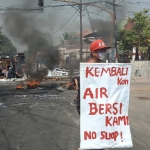 Aksi warga Desa Baujeng memprotes bau limbah dengan menutup jalan dan membakar ban.