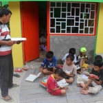 Anak-anak membaca buku di depan Poskamling RT 02 RW 01, Kelurahan Pandanwangi Blimbing Kota Malang dipandu langsung oleh Sutikno. foto: Istimewa